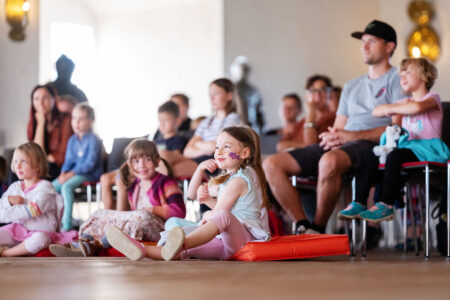 Kinder und Familien bei den Märchensonntagen im Schloss – lachende Kinder mit Gesichtsbemalung auf Kissen im Veranstaltungsraum.
