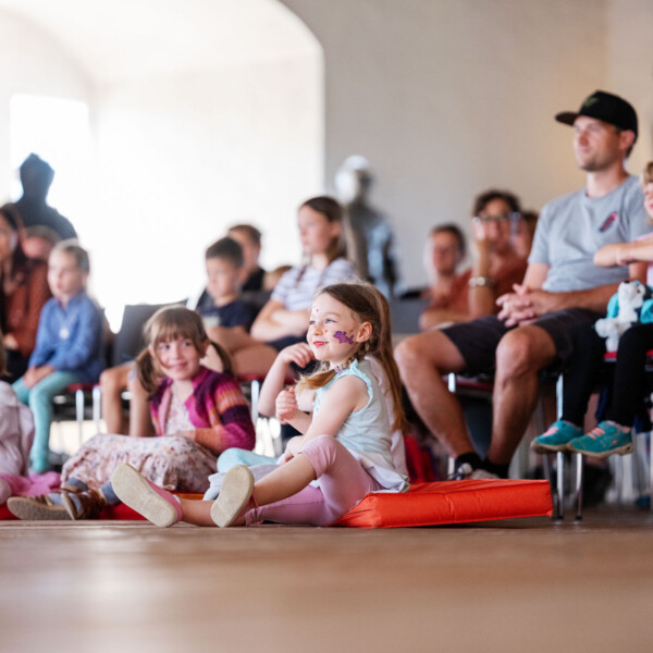 Kinder und Familien bei den Märchensonntagen im Schloss – lachende Kinder mit Gesichtsbemalung auf Kissen im Veranstaltungsraum.