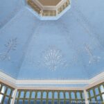 Zarte Ornamentik in Blau: Die Decke des Schallhauses auf dem Residenzschloss Heidecksburg Decke in Hellblau mit weißen Stuckmustern und umlaufenden Spitzbogenfenstern in einem achteckigen, lichtdurchfluteten Raum.