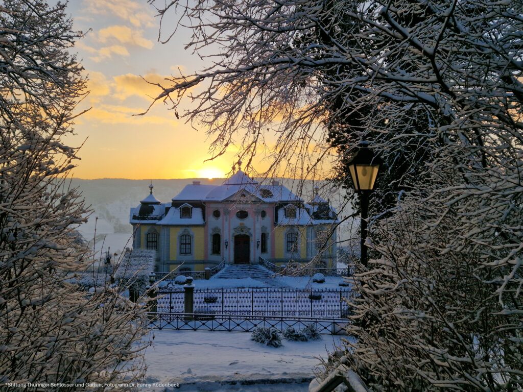 DornburgerRokokoschloss_im_Winter Rokokoschloss Dornburg im Winter, umgeben von verschneiten Bäumen und verschneitem Garten, romantische Stimmung in warmem Licht.